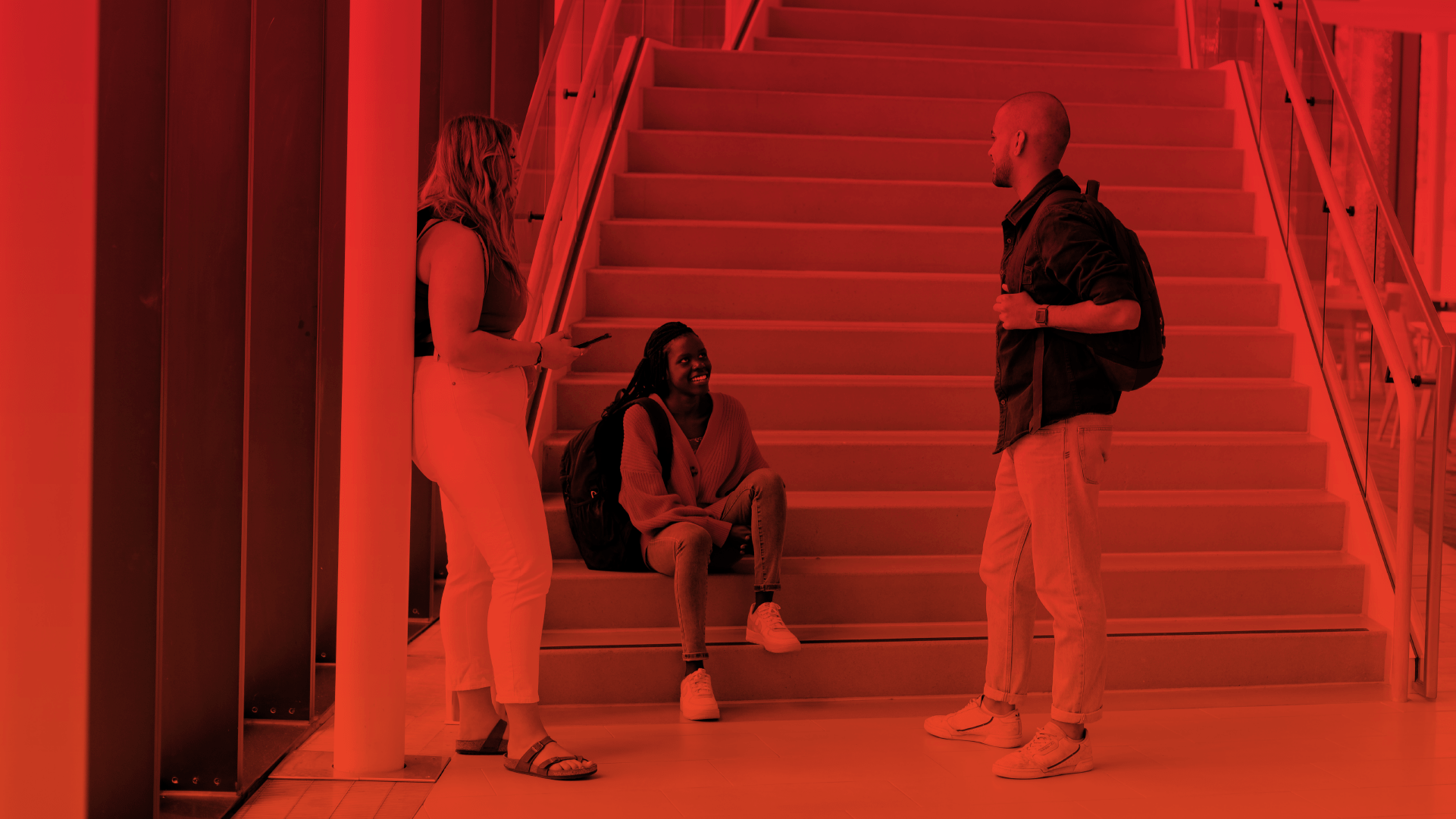 A student sitting on stairs and talking to other students