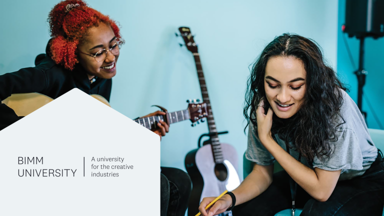 Two female students. One is playing a guitar and the other appears to be listening. A white hexagon with a BIMM university logo.
