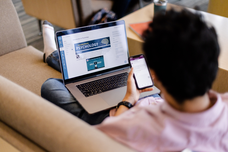 Student on laptop and phone for online and mobile learning