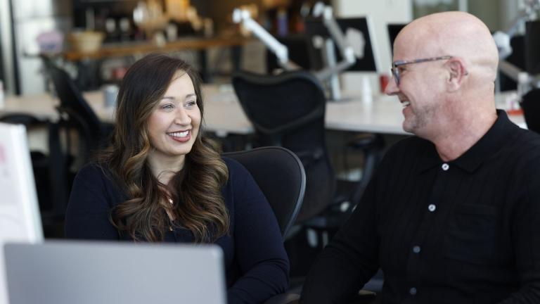 an image of a man and a woman smiling at each other while sitting in front of a computer