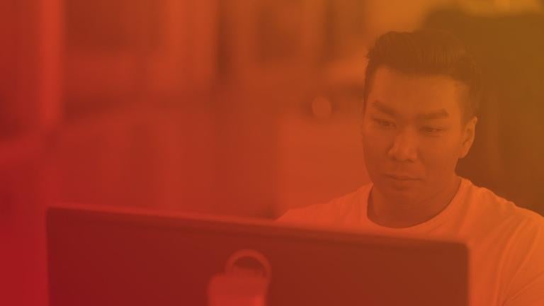 man with short hair in white shirt looking at computer screen with red overlay over image