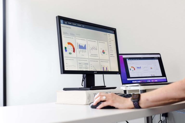 Person navigates Canvas LMS across two monitors on a desk