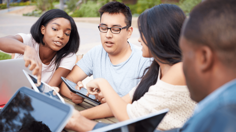 Students discussing while using devices