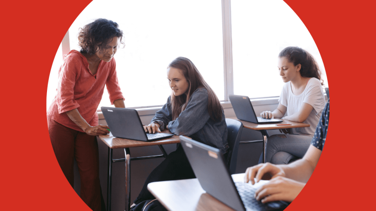 A group of diverse individuals focused on laptops while collaborating in a classroom setting.