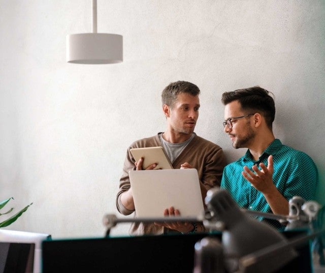 Two professionals chatting in front of a laptop
